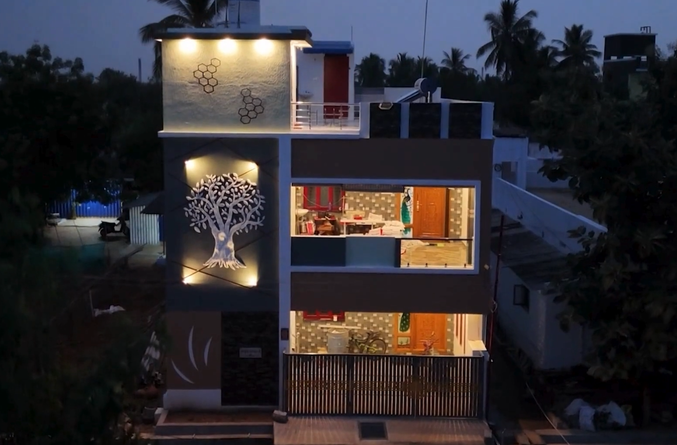A completed home lit at dusk, the stair tower carrying a cut-metal tree