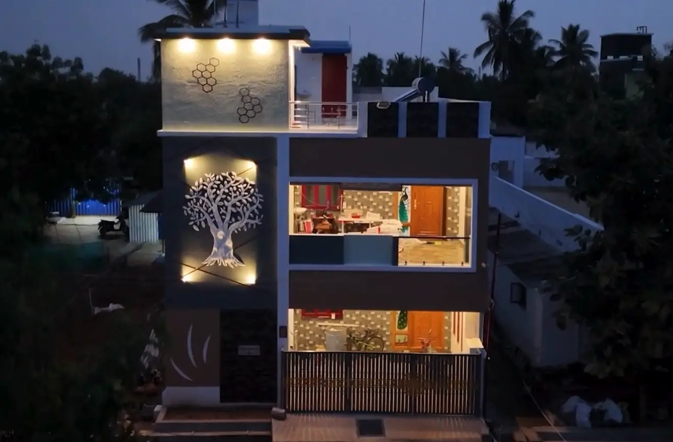 A completed home lit at dusk, the stair tower carrying a cut-metal tree