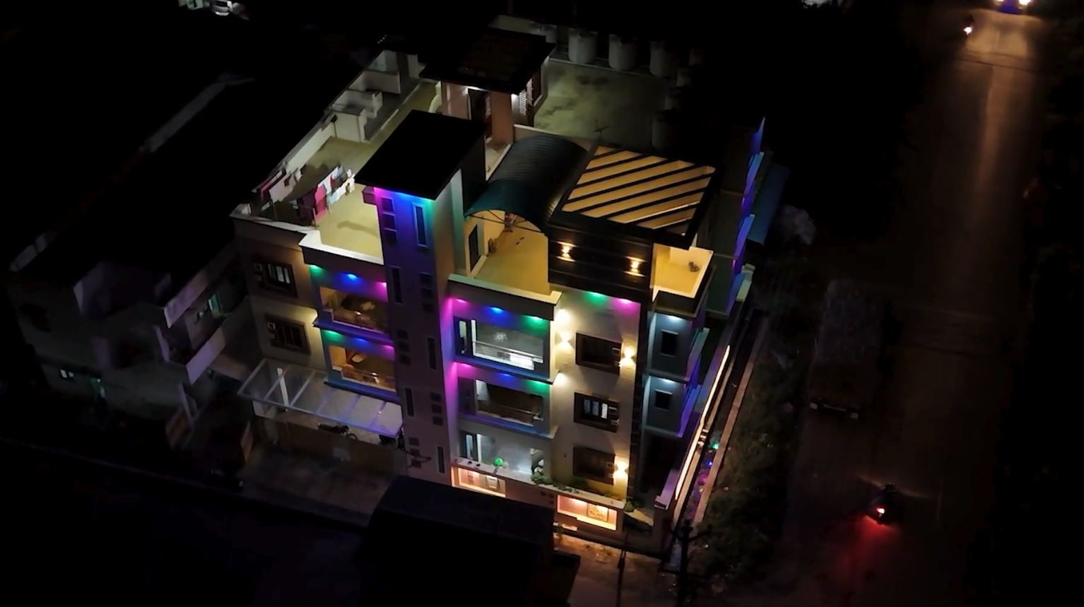 A multi-floor residence lit at night, terraces stepping back from the road
