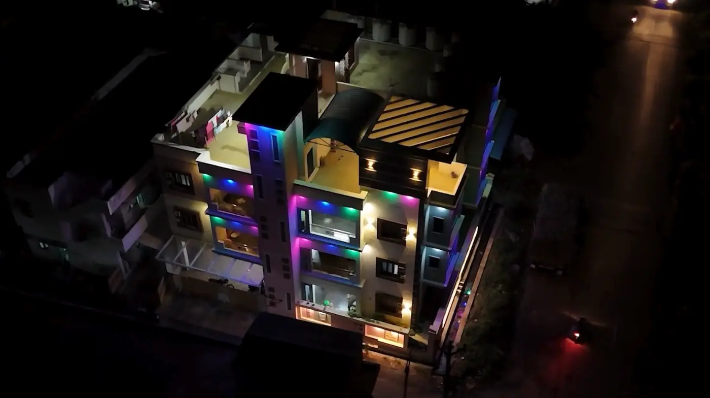 A multi-floor residence lit at night, terraces stepping back from the road