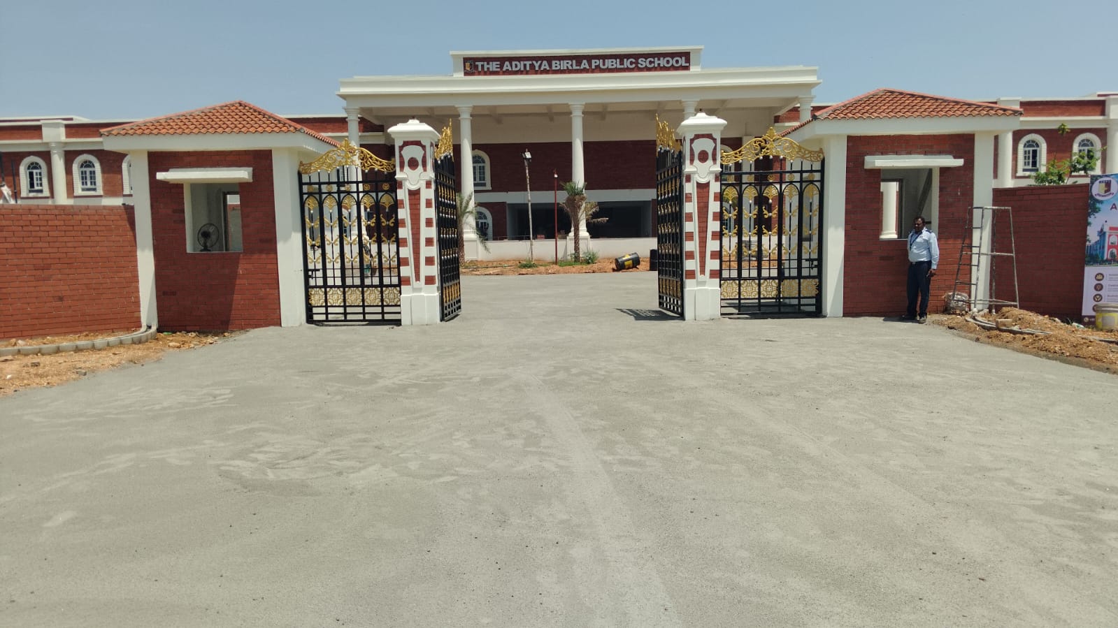 The school entrance gates and gatehouses open onto the finished drive